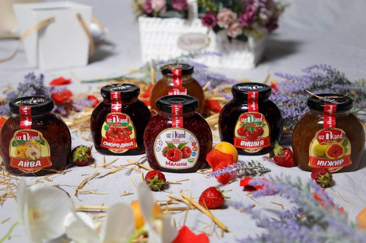 A row of UzKand fruit preserve jars with fresh berries